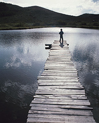 photo of man fishing off a boardwalk